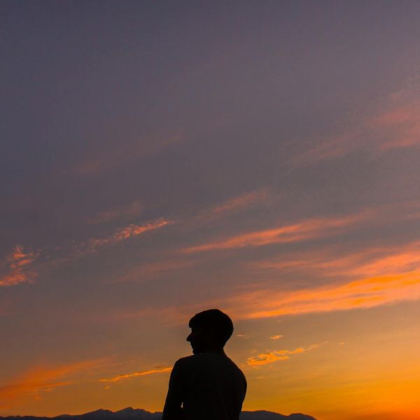 Person meditating peacefully, silhouetted against an amber-colored light source.
